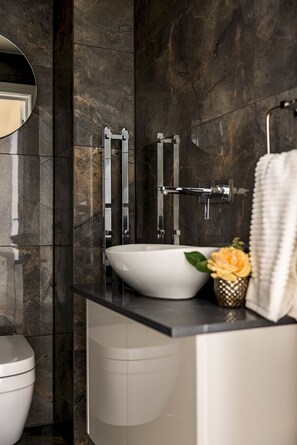 A modern bathroom with a white sink, dark marble walls, a toilet, and a mirror. - 3-bdr Stunning LUX Villa Parking Central London (London)