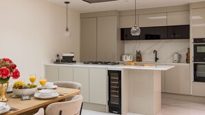 A modern kitchen with a central island, built-in appliances, and a dining area with a table set for breakfast. - 3-bdr Stunning LUX Villa Parking Central London (London)
