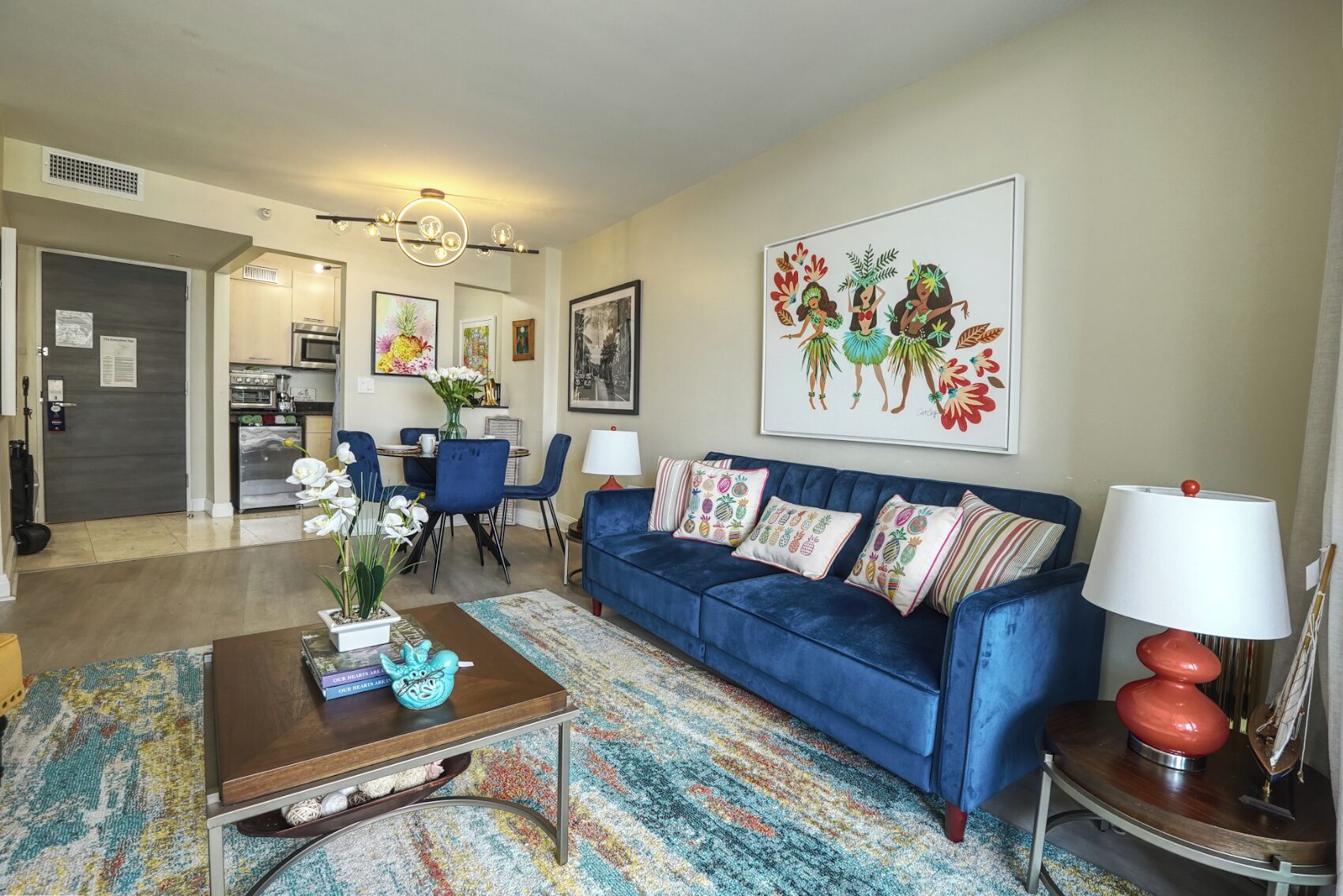 A living room with a blue sofa, a coffee table, and a dining area with chairs and a table.