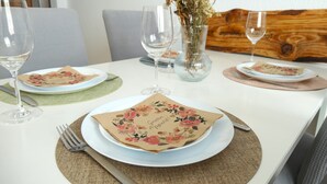 A dining table set with plates, cutlery, and glasses, with a floral napkin and a vase with dried flowers. - Cozy apartment /Central and comfortable / Only 20 min walk from the zoo (Osnabrück)