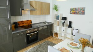 A modern kitchen with stainless steel appliances, wooden cabinets, and a dining area with a table set for two. - Cozy apartment /Central and comfortable / Only 20 min walk from the zoo (Osnabrück)
