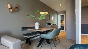 A modern dining area with a wooden table, two chairs, a bench, and a hanging pendant light. - Stylish 2-bedroom Apartment in The Hague (The Hague)