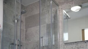 Ein modernes Badezimmer mit einer gläsernen Duschkabine, einem Holzlager und einem großen Spiegel.