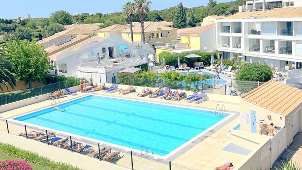 A swimming pool with sun loungers, a covered seating area, and a view of surrounding buildings. - Naturiste Cap d'Agde Port Soleil 479 (Cap d'agde)