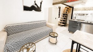 A modern interior with a patterned sofa, a small round table, a staircase, and a kitchen area. - Naturiste Cap d'Agde Port Soleil 479 (Cap d'agde)