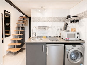 A kitchen with a built-in washing machine, a microwave, and a sink.