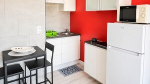 Een kleine keuken met witte kastjes, een zwart aanrecht, een magnetron en een koelkast.