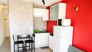 Een compacte keuken met een eethoek, een bank en een rode accentmuur.