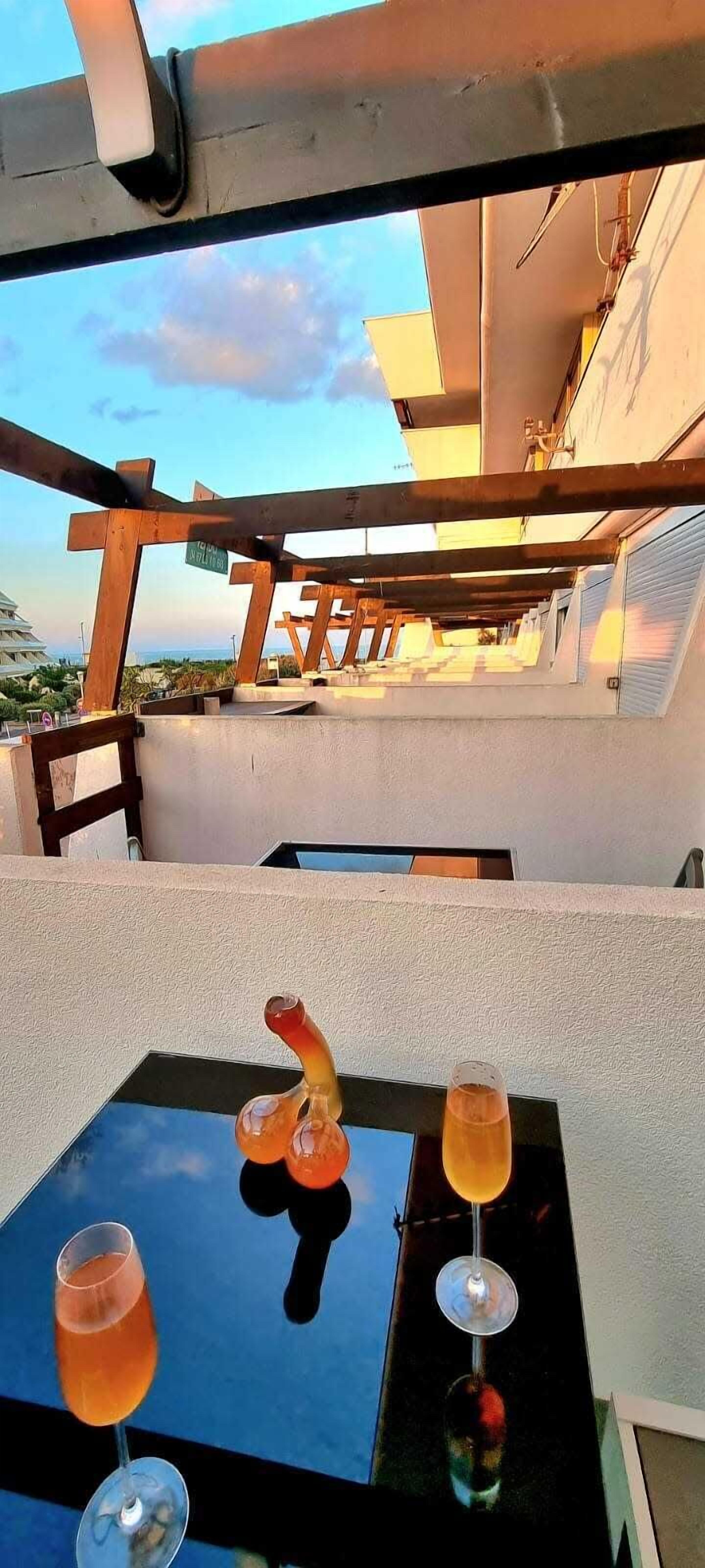 En terrass med ett bord uppdukat för drycker, med utsikt över en byggnad och himlen.