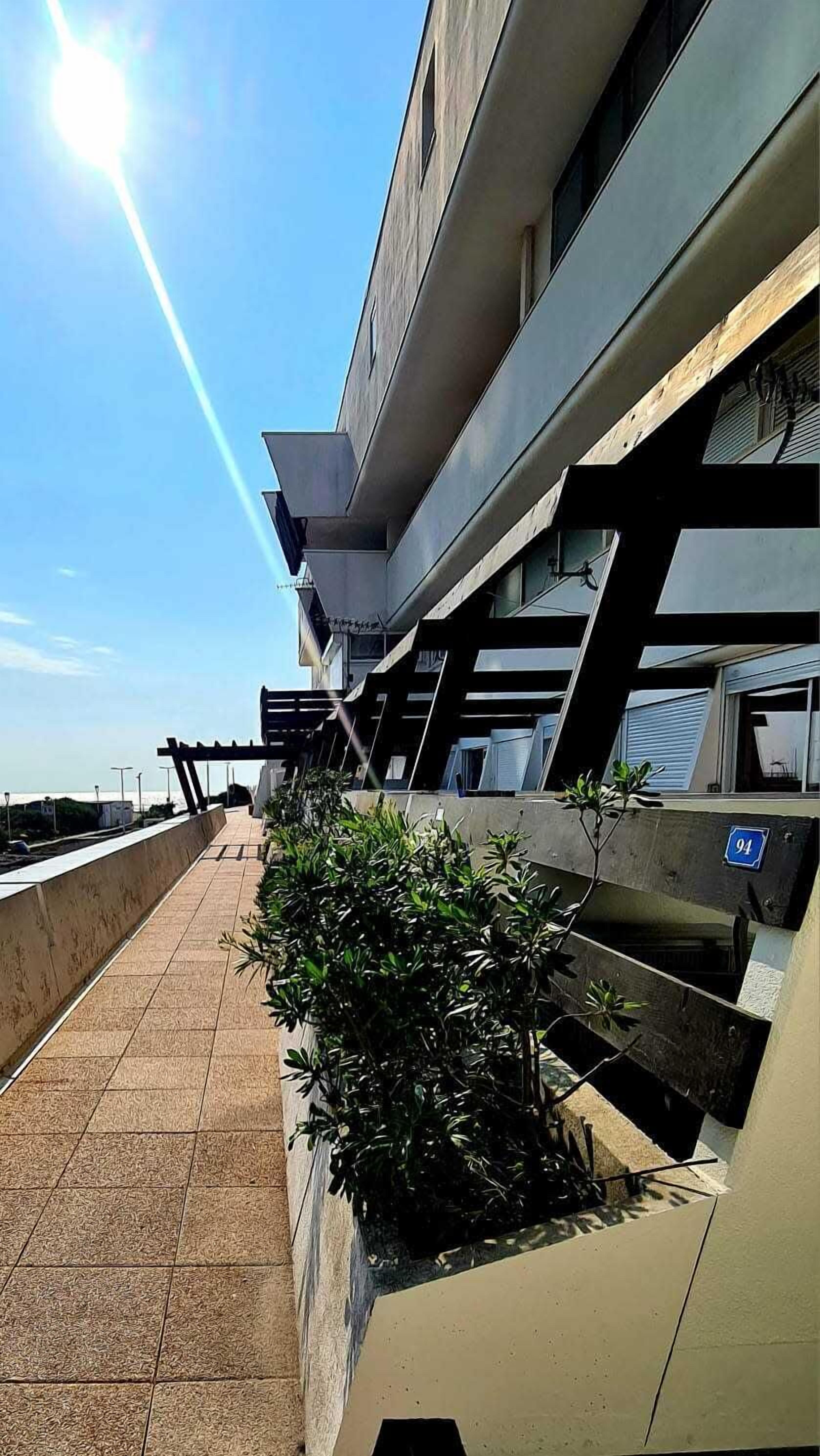 Un bâtiment moderne doté d’une terrasse-toit à surface plane, d’un espace extérieur aménagé pour s’asseoir et d’un petit jardin.