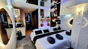 A modern hotel room with a large bed, a desk, and a bathroom.