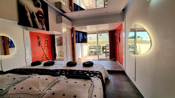 A modern hotel room with a large bed, a TV, and a view of the outdoor area.