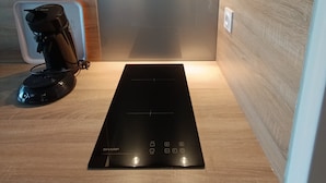 Une cuisine moderne dotée d’une plaque de cuisson à induction intégrée, d’une machine à café et d’une hotte en acier inoxydable.