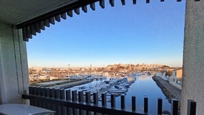 Un balcon avec vue sur une marina et des bâtiments en arrière-plan.