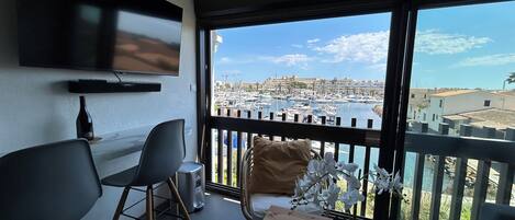 A modern living room with a TV, seating, and a view of a marina.