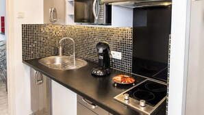 Een moderne keuken met een roestvrijstalen spoelbak, een koffieapparaat, een inductiekookplaat en een magnetron.