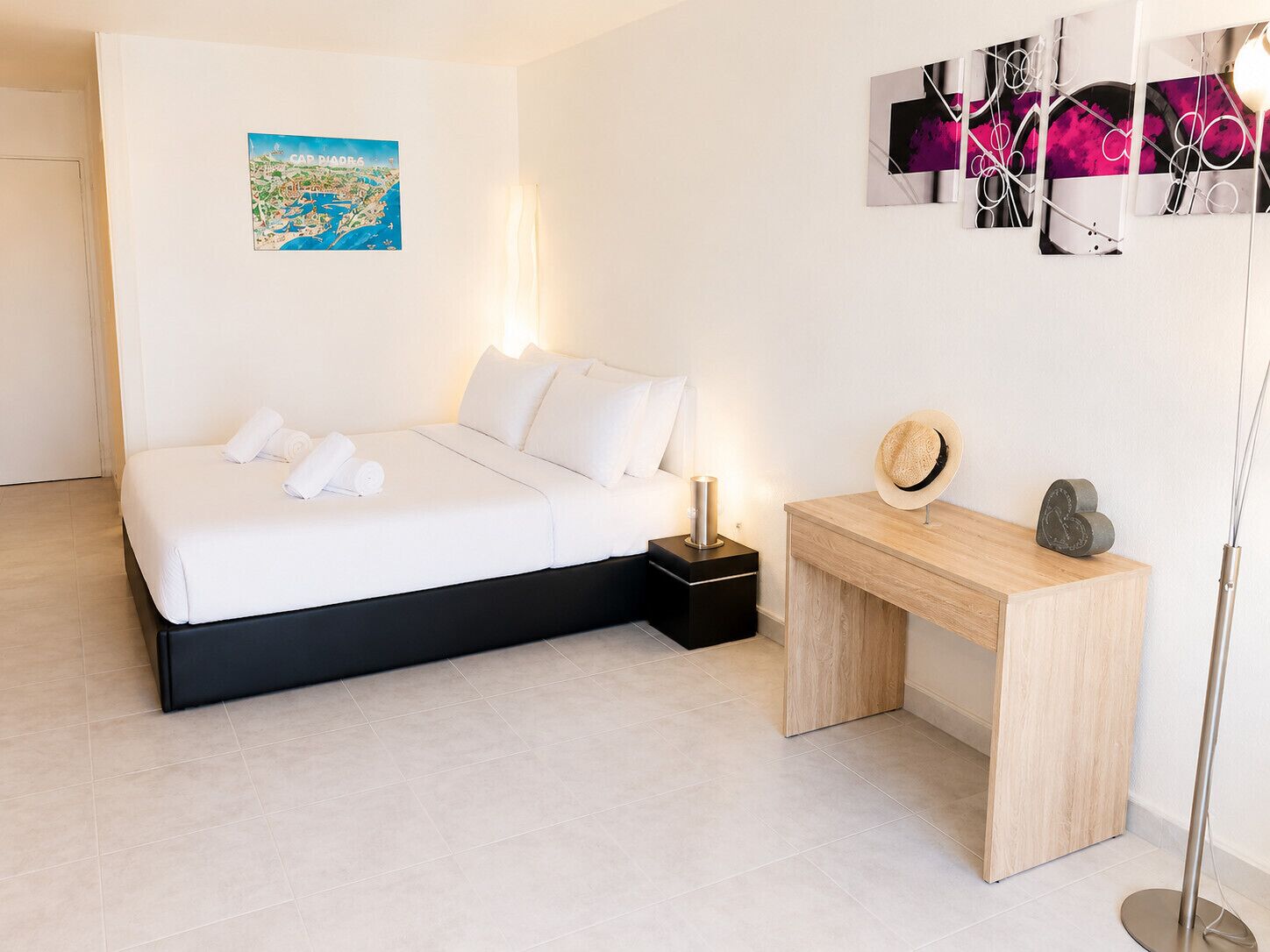 Een moderne hotelkamer met een bed, nachtkastje en een kunstwerk aan de muur.
