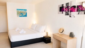 Habitación de hotel moderna con cama, mesita de noche y una obra de arte colgada en la pared.