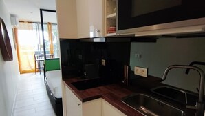 A compact kitchen with white cabinets, a wooden countertop, a stainless steel sink, and a microwave. - Naturiste Cap d'Agde Port Nature 827 ** (Agde)