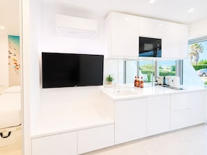 A modern kitchen with a flat-screen TV, a microwave, and a sink. - Naturiste Cap d'Agde Héliopolis AB 30 (Agde)