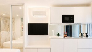 A modern kitchen with built-in appliances, a flat-screen TV, and a glass shower enclosure. - Naturiste Cap d'Agde Héliopolis AB 30 (Agde)