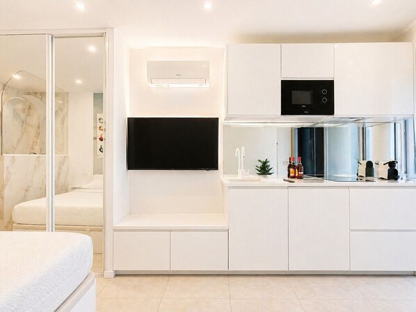 A modern kitchen with built-in appliances, a flat-screen TV, and a glass shower enclosure.