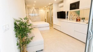 A modern kitchen with white cabinets, a built-in microwave, and a large window. - Naturiste Cap d'Agde Héliopolis AB 30 (Agde)