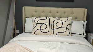 A neatly made bed with a white duvet, two pillows with black patterns, and a rolled white towel. - Modern 2 Bedroom City Oasis in Manchester (Manchester)