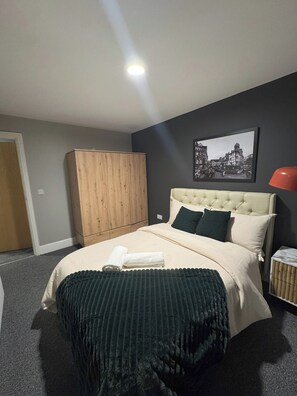 A bedroom with a bed, a wardrobe, a framed picture on the wall, and a red lamp. - Modern 2 Bedroom City Oasis in Manchester (Manchester)