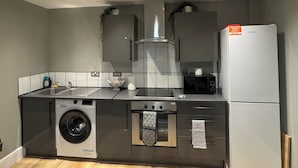 A compact kitchen with a washing machine, oven, microwave, and refrigerator. - Modern 2 Bedroom City Oasis in Manchester (Manchester)