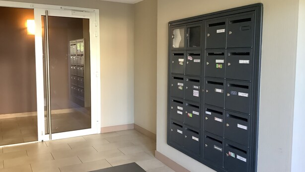 A hallway with a mail slot wall unit and a door leading to a room with a tiled floor. - Résidence Eihera BuildingB (Hendaye)