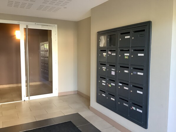 A hallway with a mail slot wall unit and a door leading to a room with a tiled floor. - Résidence Eihera BuildingB (Hendaye)