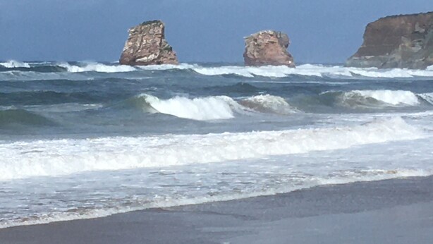 A beach with waves crashing onto the shore and large rock formations in the background. - Résidence Eihera BuildingB (Hendaye)