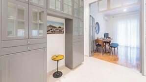 A modern room with a dining area, a small table, and a cabinet with glass doors. - Cozy home in Athens (Nea Smirni)