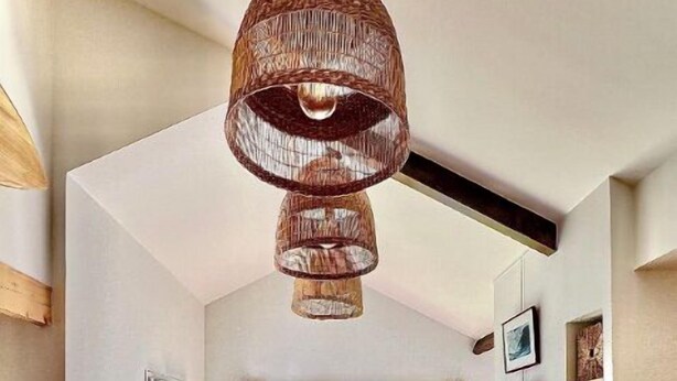 A modern dining area with a long table, chairs, and a hanging light fixture.