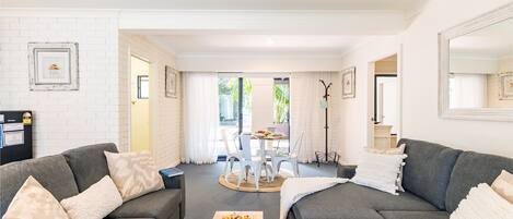 A modern living room with two grey sofas, a coffee table, and a dining area with a table and chairs.
