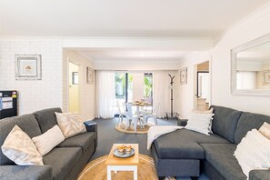 A modern living room with two grey sofas, a coffee table, and a dining area with a table and chairs.