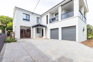 A modern two-story house with a garage, a covered entryway, and a balcony.