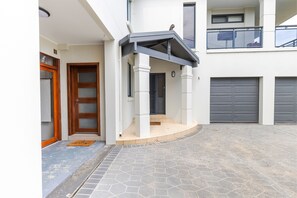 Een woongebouw met een voordeur, een overdekte veranda, een garage en een balkon.
