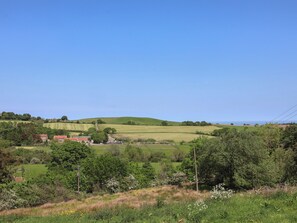 Rolling hills, a clear sky, and a rural landscape with buildings.