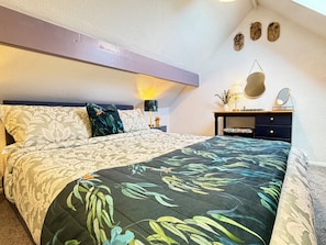 Quarto com cama, mesa de cabeceira, luminária e obra de arte na parede.