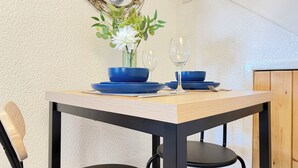 A dining table with blue tableware and a vase of flowers, set against a textured wall with a clock. - Wayside Farm Cart Cottage (Scarborough)