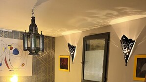 Un dormitorio con una cama grande, un farol colgante, un ventanal con vistas y un cuadro colgado en la pared.