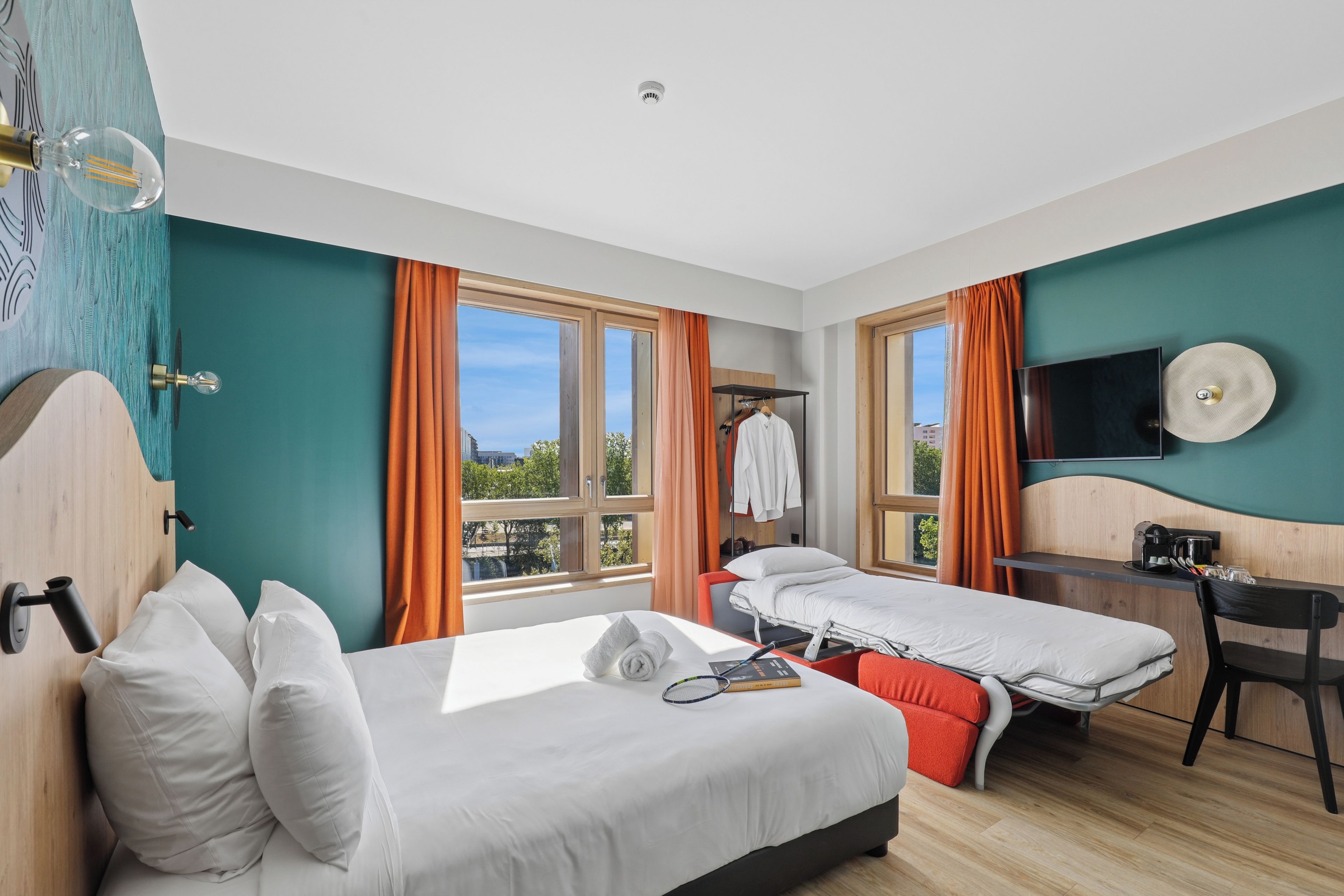 Une chambre d’hôtel avec deux lits, un bureau, une télévision et une vue sur l’extérieur.