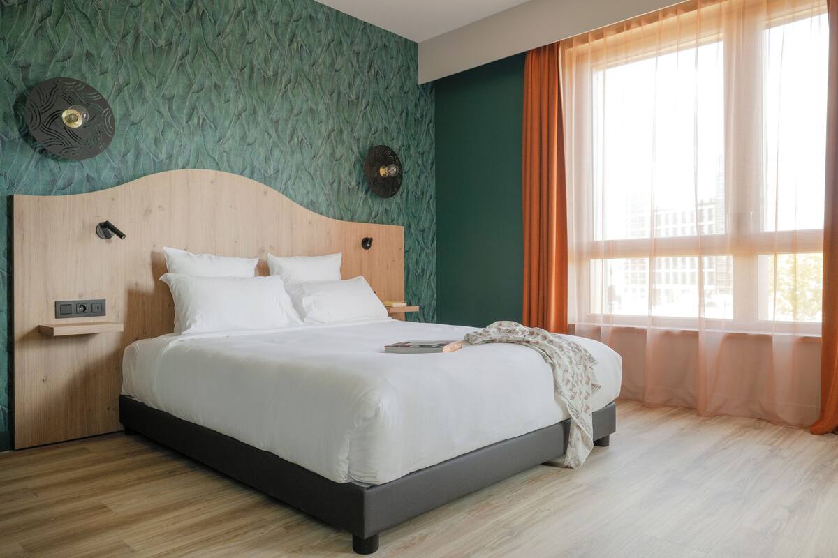 A neatly made bed with white linens, a wooden headboard, and a bedside table with a lamp.