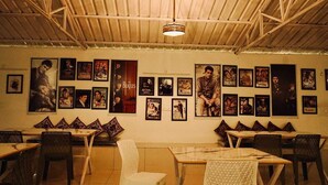 A restaurant with a wooden ceiling and walls adorned with movie posters. Tables and chairs are arranged for dining. - The Himaya's resort  (Rishikesh)