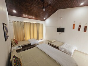 Une chambre d’hôtel avec deux lits, un ventilateur de plafond, une télévision et une fenêtre avec des rideaux.