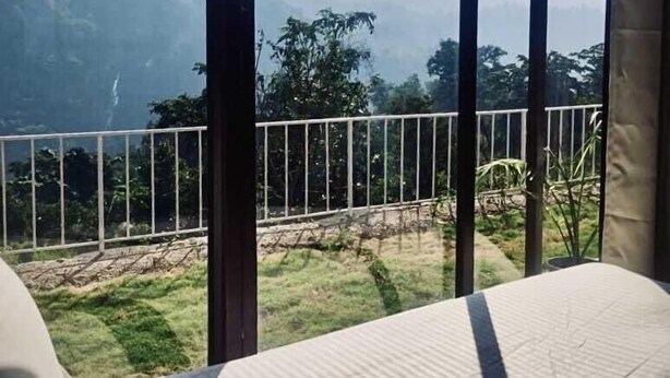 A room with a bed and a view of a mountainous landscape through large windows. - The Himaya's resort  (Rishikesh)