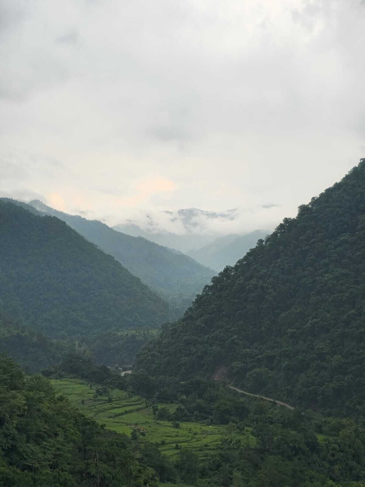 Une vallée parsemée de terrasses agricoles et traversée par une route sinueuse.