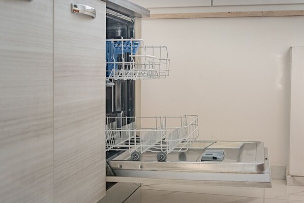 An open dishwasher with two racks and a control panel.